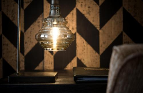 a glass lamp on a table with a book at Leonardo Hotel Antwerp The Plaza in Antwerp