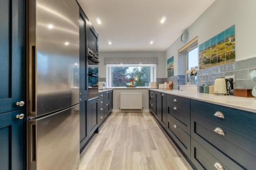 a kitchen with blue cabinets and a stainless steel refrigerator at Vincent Studio in Snape
