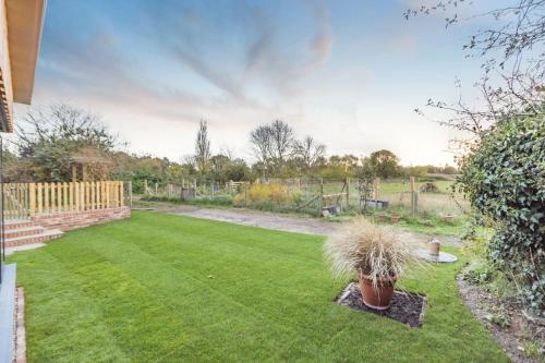 a backyard with a lawn with plants and a fence at Vincent Studio in Snape