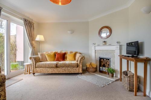 a living room with a couch and a fireplace at Honeysuckle in Halesworth