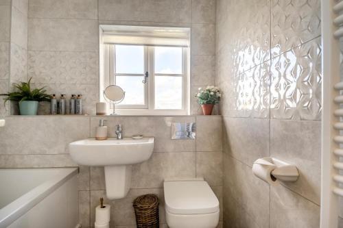 a bathroom with a sink and a toilet and a window at Honeysuckle in Halesworth