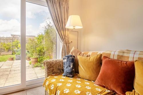 a living room with a couch and a large window at Honeysuckle in Halesworth