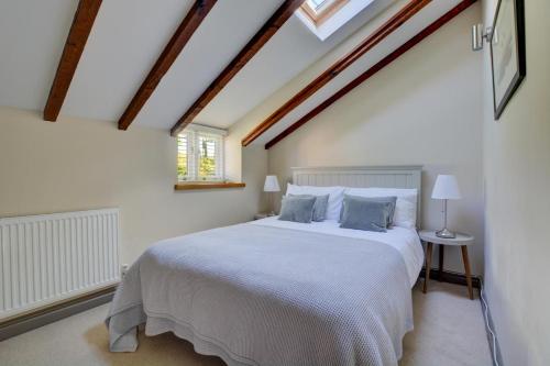 a bedroom with a large white bed in a attic at Bridge Cottage in North Creake