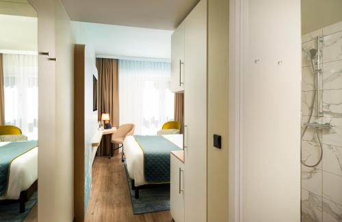a hotel room with two beds and a bathroom at Leonardo Hotel Hamburg Altona in Hamburg
