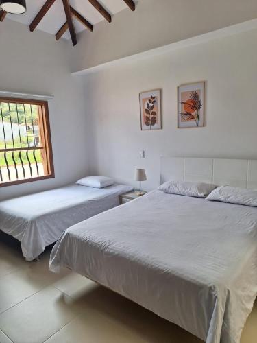 two beds in a white room with a window at Casa Nueva en Zapatoca in Zapatoca