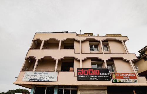 a tall building with a sign in front of it at Super Hotel O Sushma Lodge in Manipala