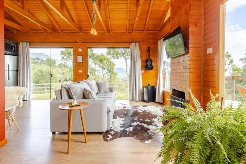 a living room with a couch and a fireplace at Cabana Romântica na Serra com Hidro, Lareira, Lagos e Trilhas in Bom Retiro