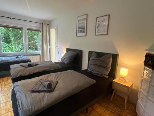 ein Schlafzimmer mit zwei Betten und einem Tisch mit Lampe in der Unterkunft SeeNah Apartments, Komfort mit Einkaufsmöglichkeiten & Parkplatz in Bad Zwischenahn