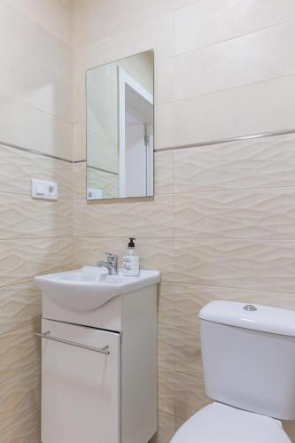 a bathroom with a toilet and a sink and a mirror at Blue Río Playa, Casa & Studio in Costa Calma