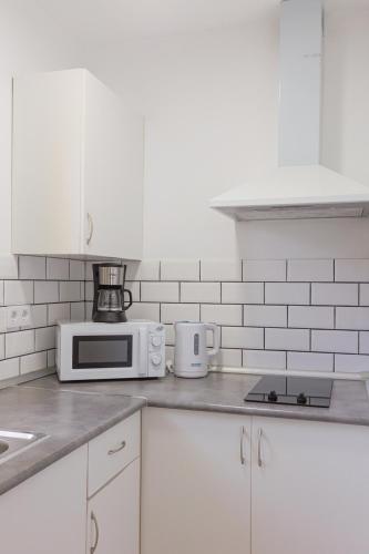 a kitchen with white cabinets and a microwave at Blue Río Playa, Casa & Studio in Costa Calma