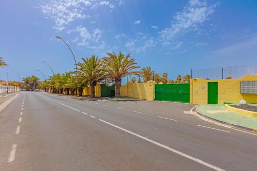 an empty street with palm trees and a fence at Blue Río Playa, Casa & Studio in Costa Calma