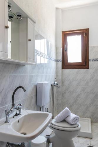 a white bathroom with a sink and a toilet at Fotini Rooms in Skopelos Town