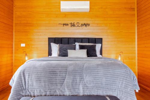 a bedroom with a bed with a wooden wall at Cabana Romântica na Serra com Hidro, Lareira, Lagos e Trilhas in Bom Retiro