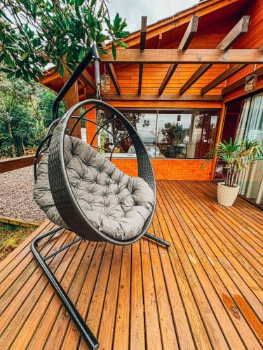 a swing chair sitting on a deck at Cabana Romântica na Serra com Hidro, Lareira, Lagos e Trilhas in Bom Retiro