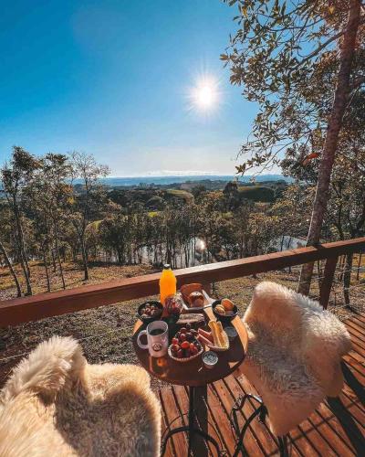 a dog sitting on a deck with a table with food at Cabana Romântica na Serra com Hidro, Lareira, Lagos e Trilhas in Bom Retiro