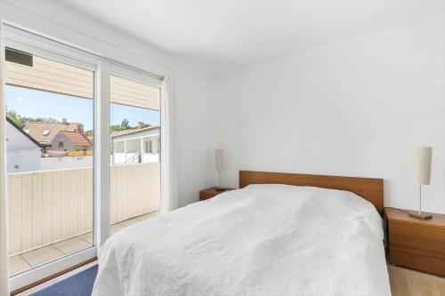 a bedroom with a white bed and a large window at 5633-Gudhjem-Kirkevej-10-lejl-19 in Gudhjem