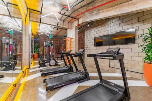 a gym with several tread machines and a flat screen tv at Linked Batel by Xtay - Experiencia moderna a passos do Hard Rock in Curitiba