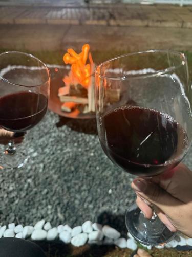two people holding glasses of red wine in front of a fire at Chácara com piscina e churrasqueira in Itatiba