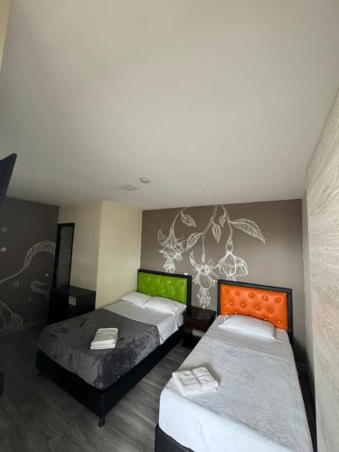 a bedroom with two beds and a painting on the wall at HOTEl LAS FLORES in Santa Rosa de Cabal