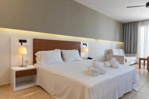 a bedroom with a large white bed with two towels on it at The Noverian Scenic Crete 5 Star Hilltop Villa Resort & Spa in Malia