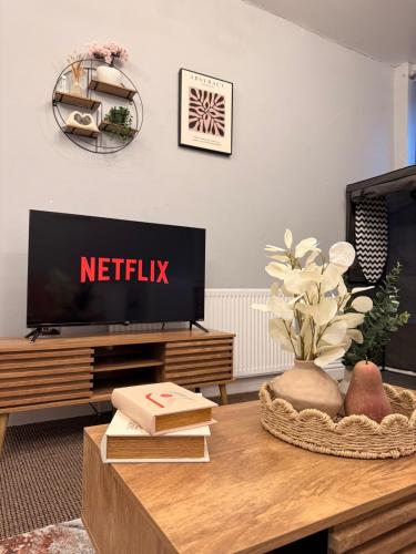 a living room with a television and a table at Oldham city centre studio in Oldham