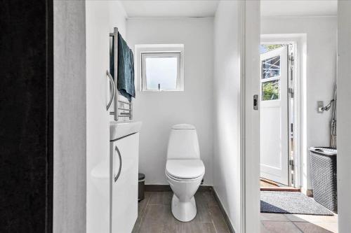 a white bathroom with a toilet and a window at 6736-Allinge-Thorkildsvej-8 in Allinge