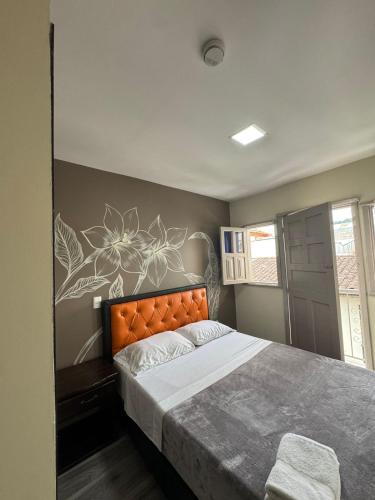 a bedroom with a large bed with an orange headboard at HOTEl LAS FLORES in Santa Rosa de Cabal