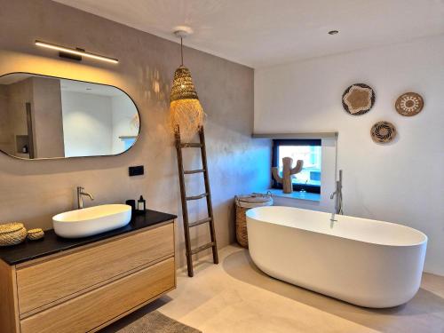 a bathroom with a large tub and a large mirror at Chez Simone Liège, bain nordique in Boncelles