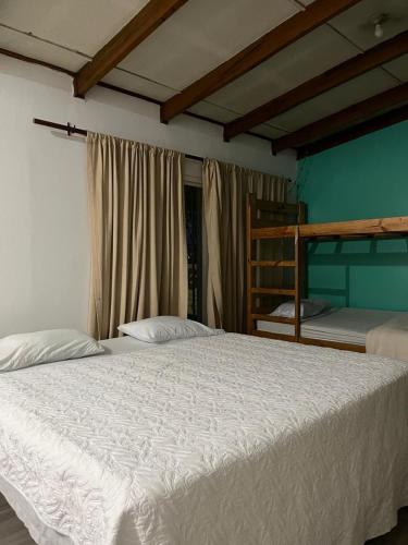a bedroom with a large white bed and bunk beds at Gaudy's Hotel in San José