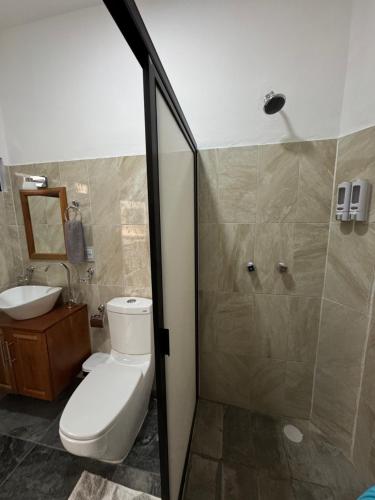 a bathroom with a toilet and a shower and a sink at Houzze Plety in Brisas de Zicatela