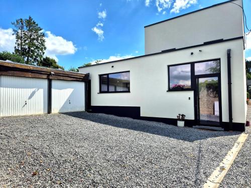 a white house with black windows and a driveway at Chez Simone Liège, bain nordique in Boncelles