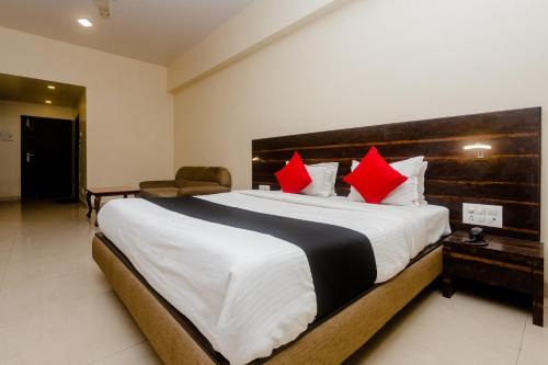 a bedroom with a large bed with red pillows at Hotel O Sai Plaza in Kalyan