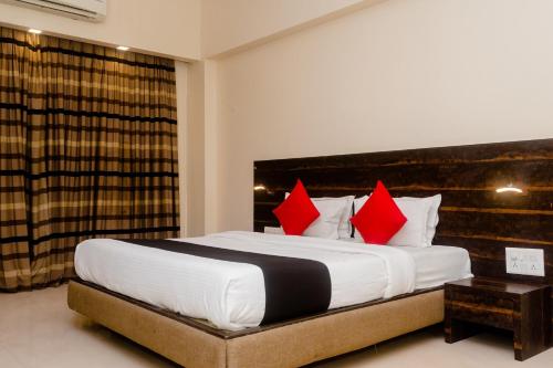 a bedroom with a large bed with red pillows at Hotel O Sai Plaza in Kalyan