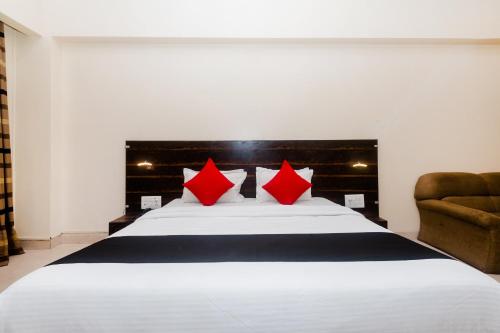a bedroom with a large white bed with red pillows at Hotel O Sai Plaza in Kalyan