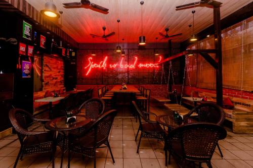 a restaurant with tables and chairs and neon signs at Hotel O Sai Plaza in Kalyan