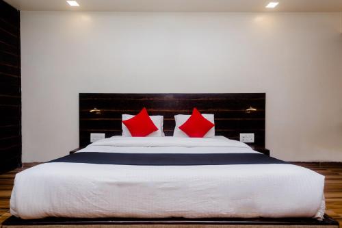 a bedroom with a large bed with red pillows at Hotel O Sai Plaza in Kalyan