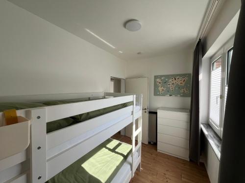 a bedroom with a white bunk bed and a window at Vier Nordlichter Erdgeschosswohnung mit Terrasse und Garten in Bensersiel