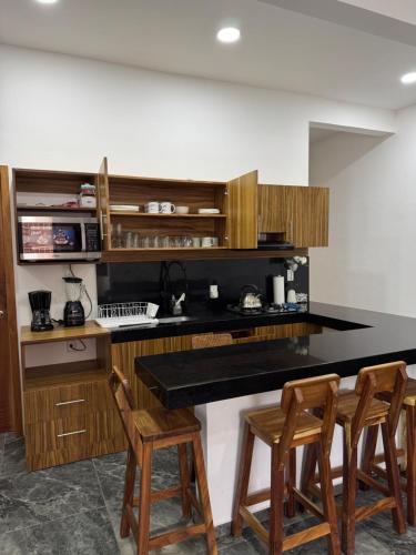 a kitchen with a black counter and wooden cabinets at Houzze Plety in Brisas de Zicatela