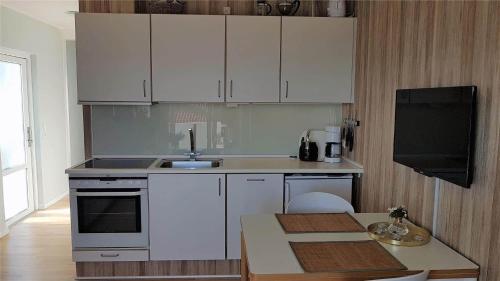 a kitchen with white cabinets and a sink and a table at 5505-Gudhjem-Kirkevej-10-Lejl-20 in Gudhjem