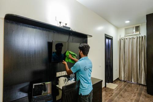 a man painting a wall in a room at Galleria Inn -Galleria Market & Golf Course in Gurgaon
