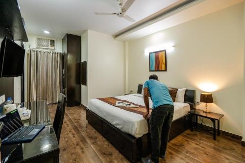a man making a bed in a hotel room at Galleria Inn -Galleria Market & Golf Course in Gurgaon
