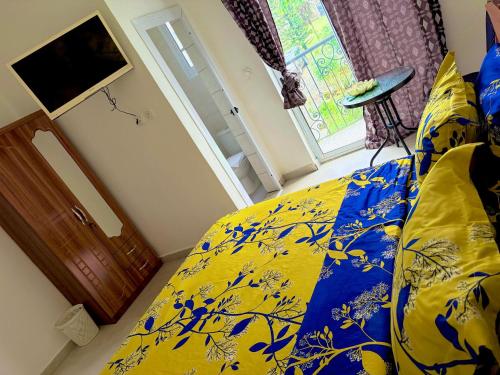 a bedroom with a bed with a blue and yellow comforter at Jacobs Hôtel in Douala