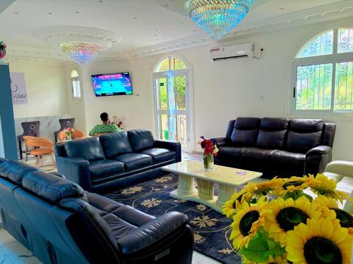 a living room with couches and a table with flowers at Jacobs Hôtel in Douala