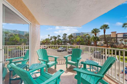 a balcony with green chairs and tables and palm trees at Beach Cottage 1104 in Clearwater Beach