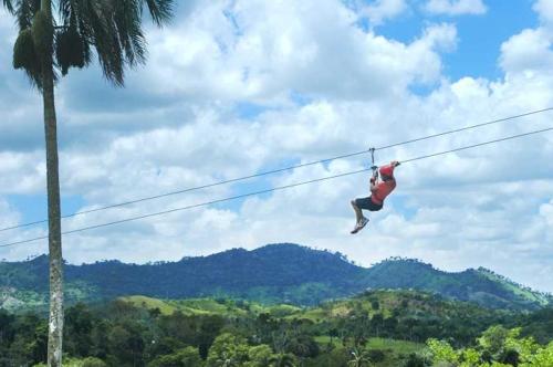 a person is hanging on a zip line at DUCASSI DELUXE playa LOS CORALES - rooftop pool and restaurants in Punta Cana