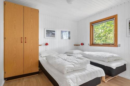 a bedroom with two beds and a cabinet and a window at 4706-Aakirkeby-Sondre-Landevej-58 in Åkirkeby