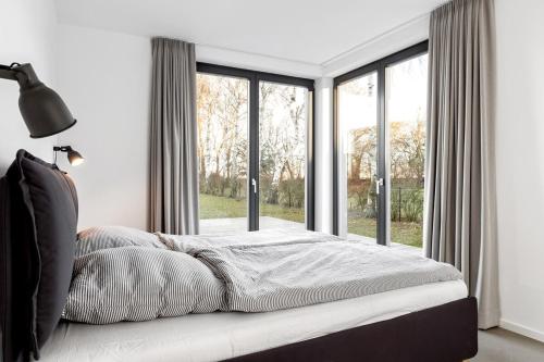 a bedroom with a bed and a large window at Haus Berta Exklusives Architektenhaus Fehmarn, strandnah in Fehmarn