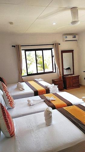 a room with three beds and a large window at Kounous Self-Catering Apartments in La Réunion