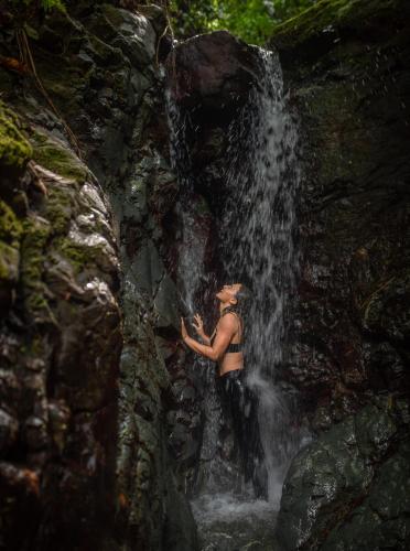a woman standing in front of a waterfall at Dolphin Quest Jungle Lodge in Piedras Blancas