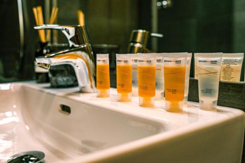 a row of orange juice cups sitting on a bathroom sink at Luxury Apartments Pivovarské domy in Hradec Králové